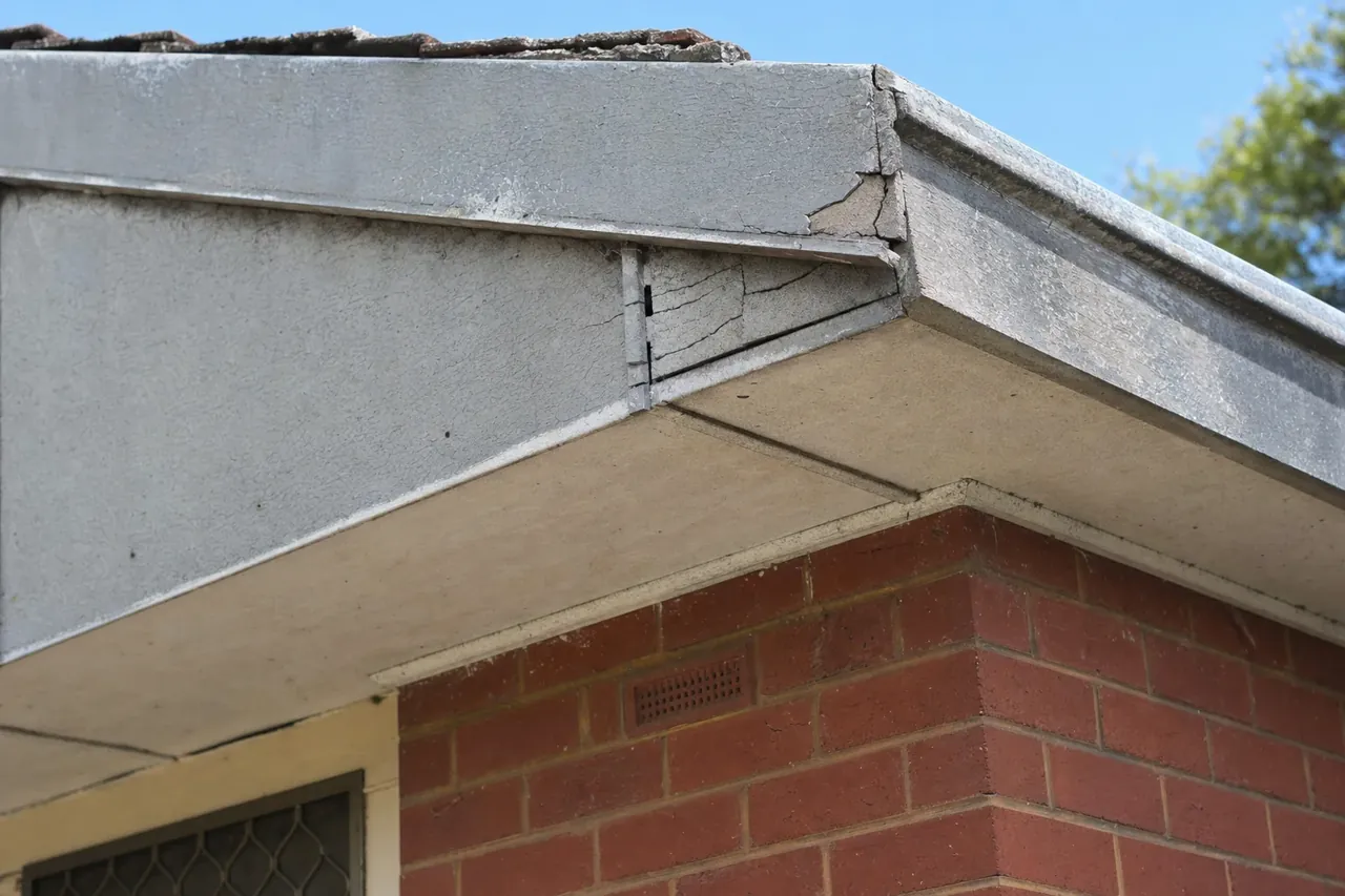 Weathered grey fibre-cement eaves and soffit lining under the roofline of an older Perth brick home